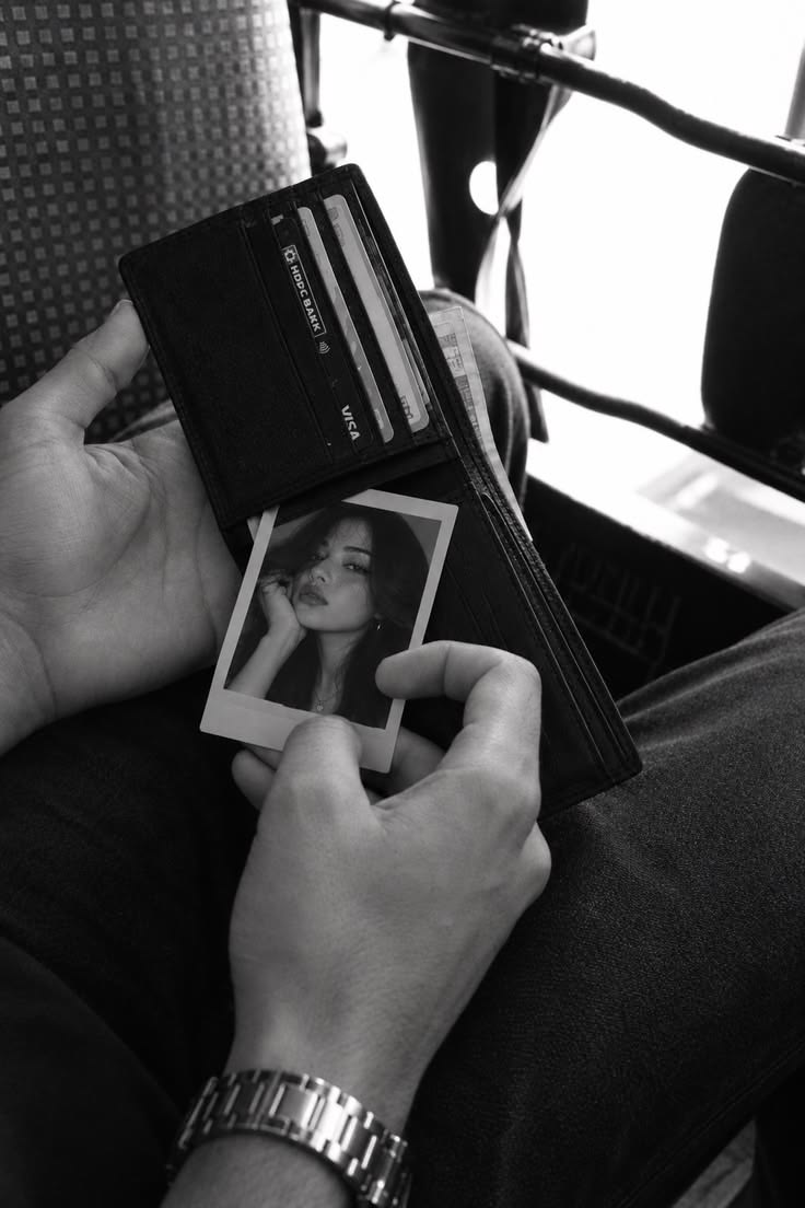 A hand holding a small printed photograph, in black and white.